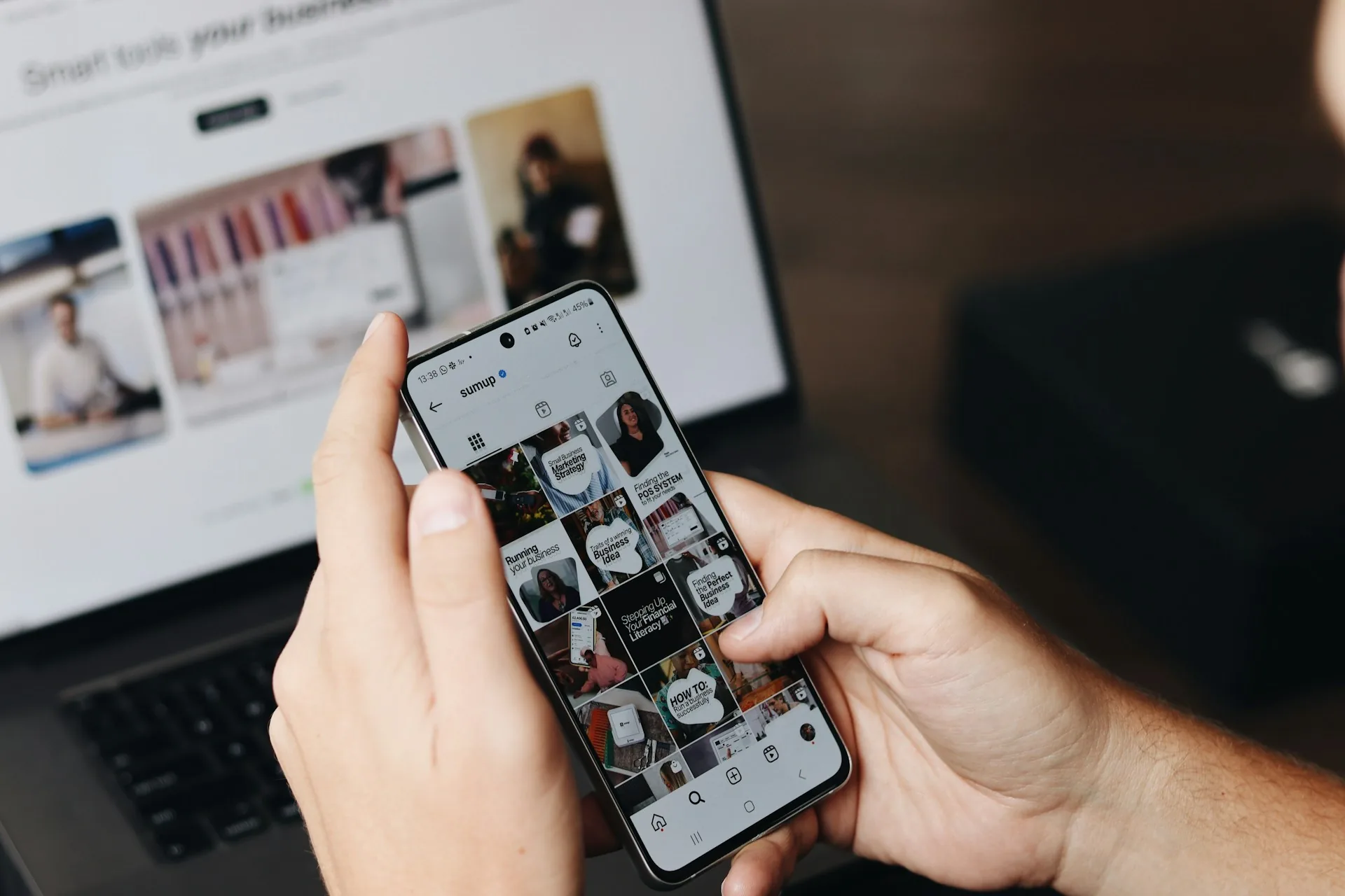 Persona revisando contenido de redes sociales en el móvil junto al portátil