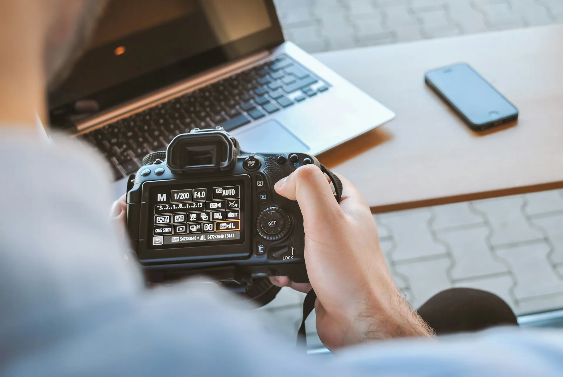 Filmmaker reviewing footage on a laptop next to a professional DSLR camera