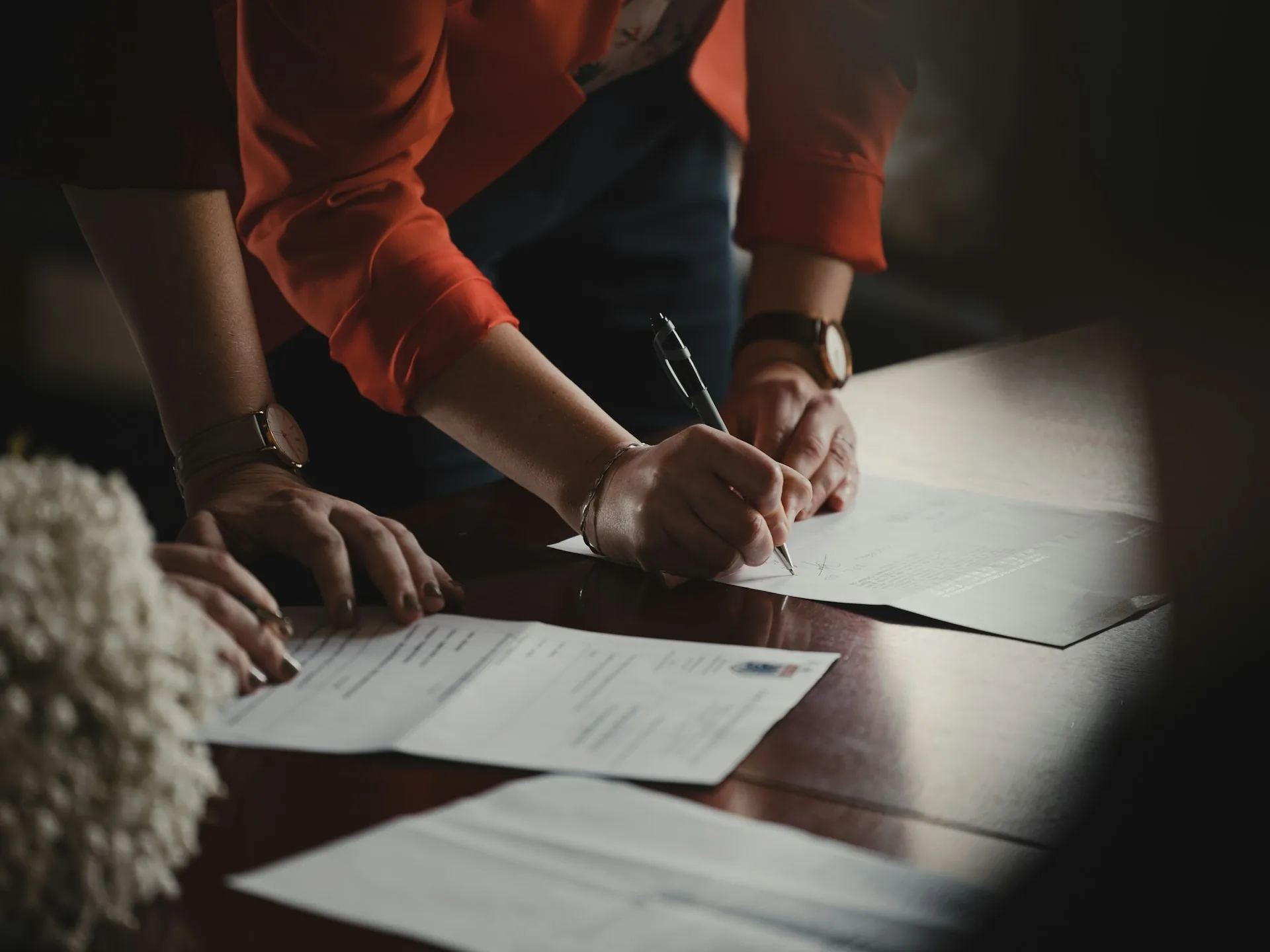 Dos personas firmando un documento de acuerdo sobre una mesa