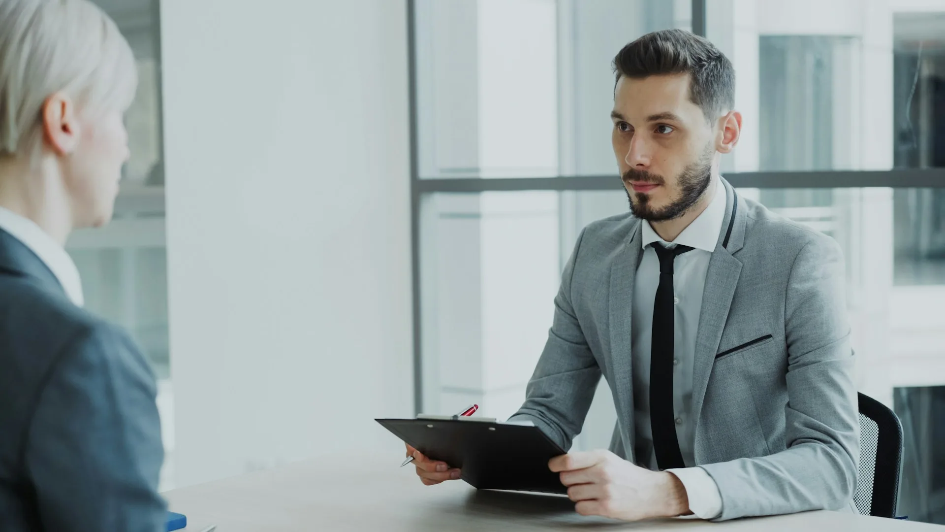 Corporate interview in a modern office, two people sitting face to face in natural light