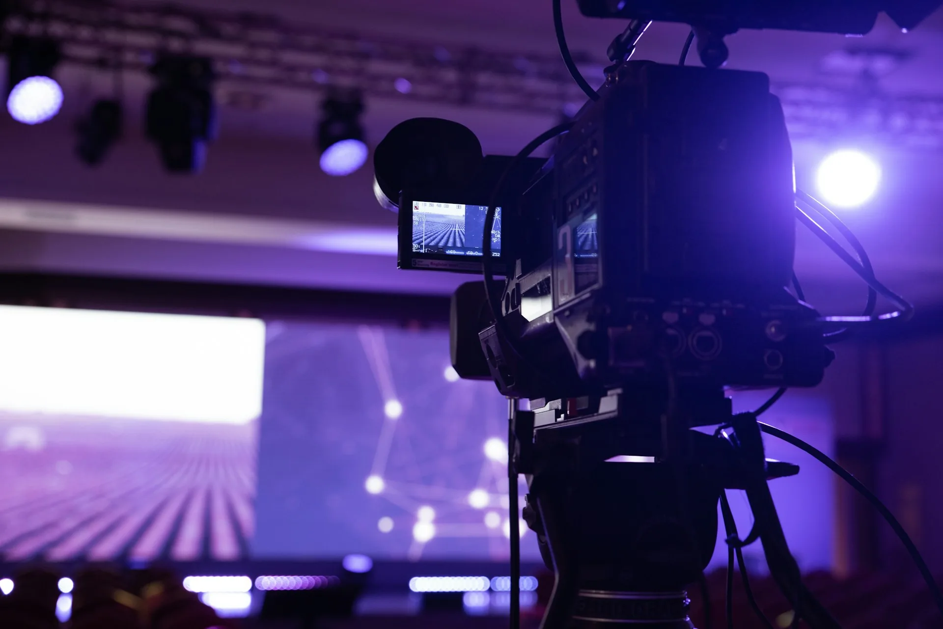 Cámara de vídeo sobre trípode grabando un escenario durante un evento
