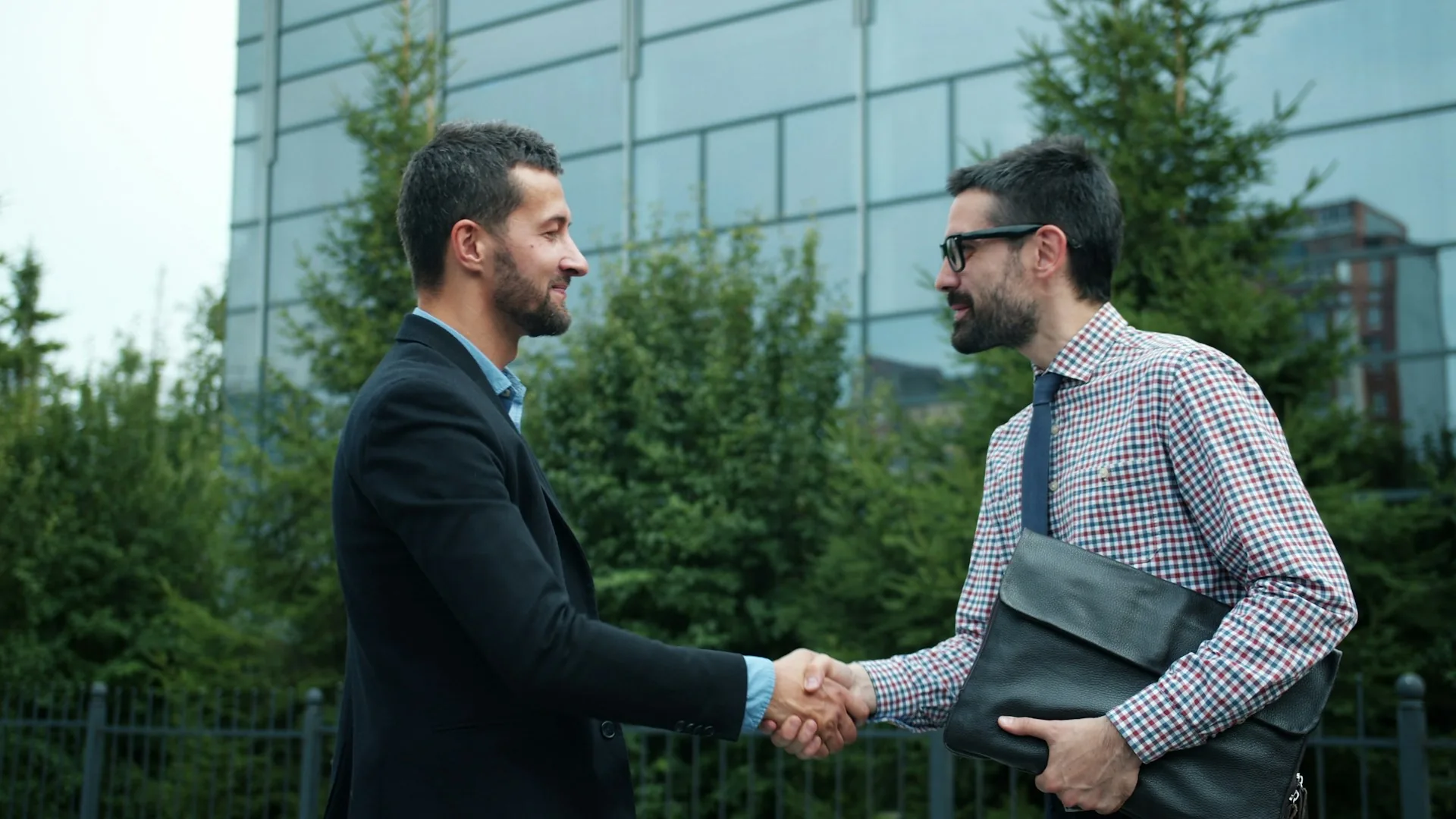 Two business partners shaking hands at the entrance of a modern office