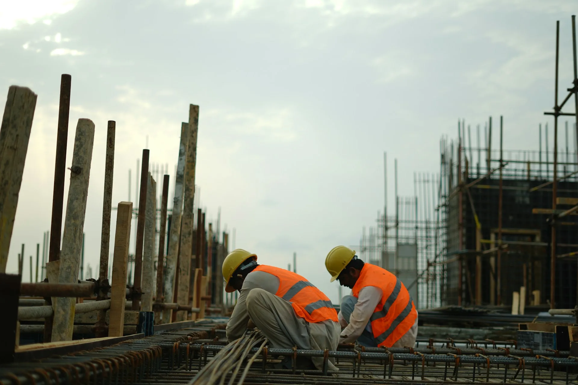 Two workers in hard hats and high-visibility vests working on a construction site