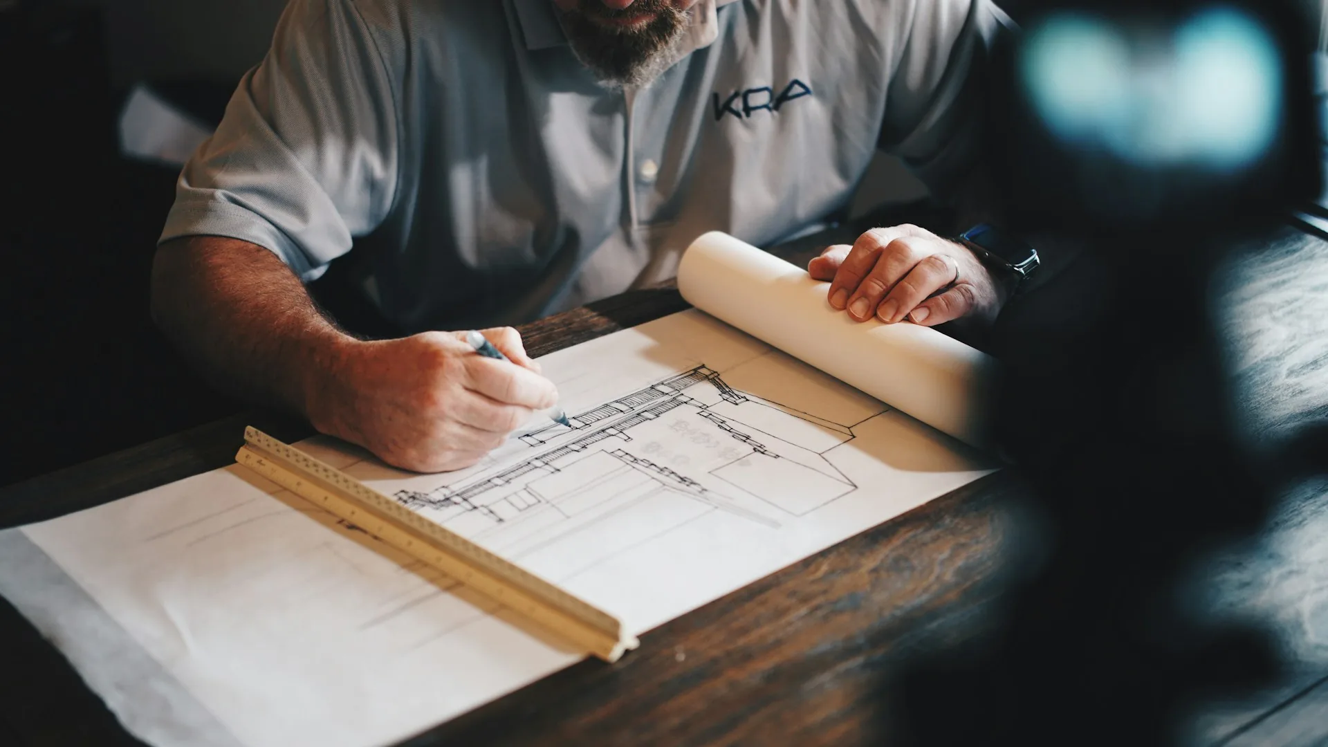 Arquitecto trabajando sobre un plano con lápiz y regla en su mesa