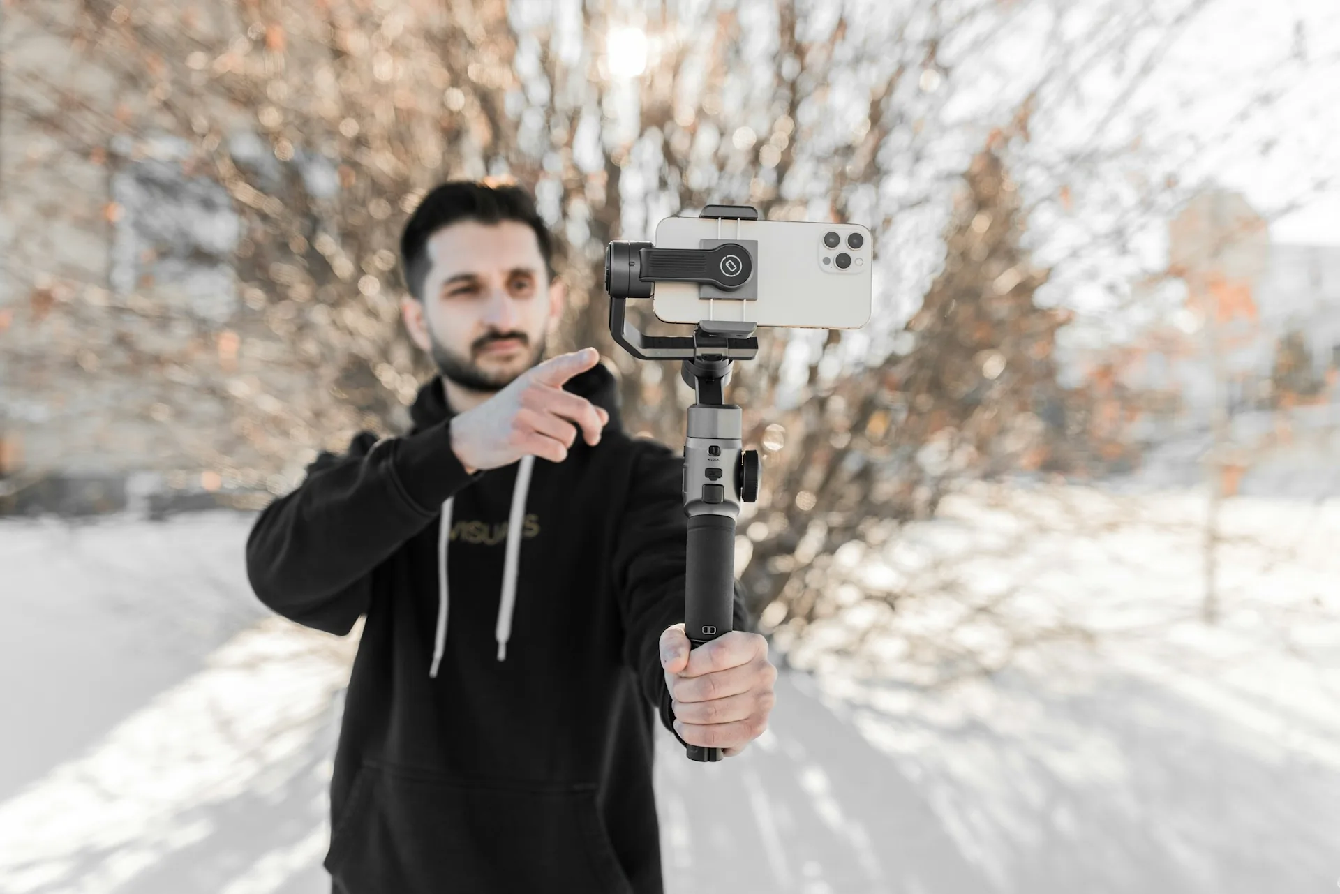 Man holding a phone mounted on a gimbal stabilizer outdoors