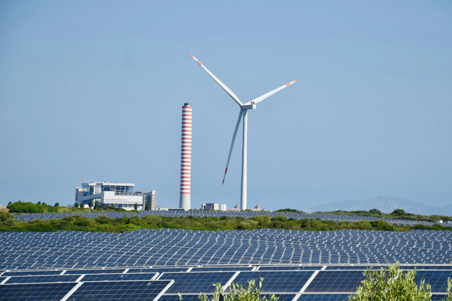 Wind farm with turbines next to solar panels at sunset