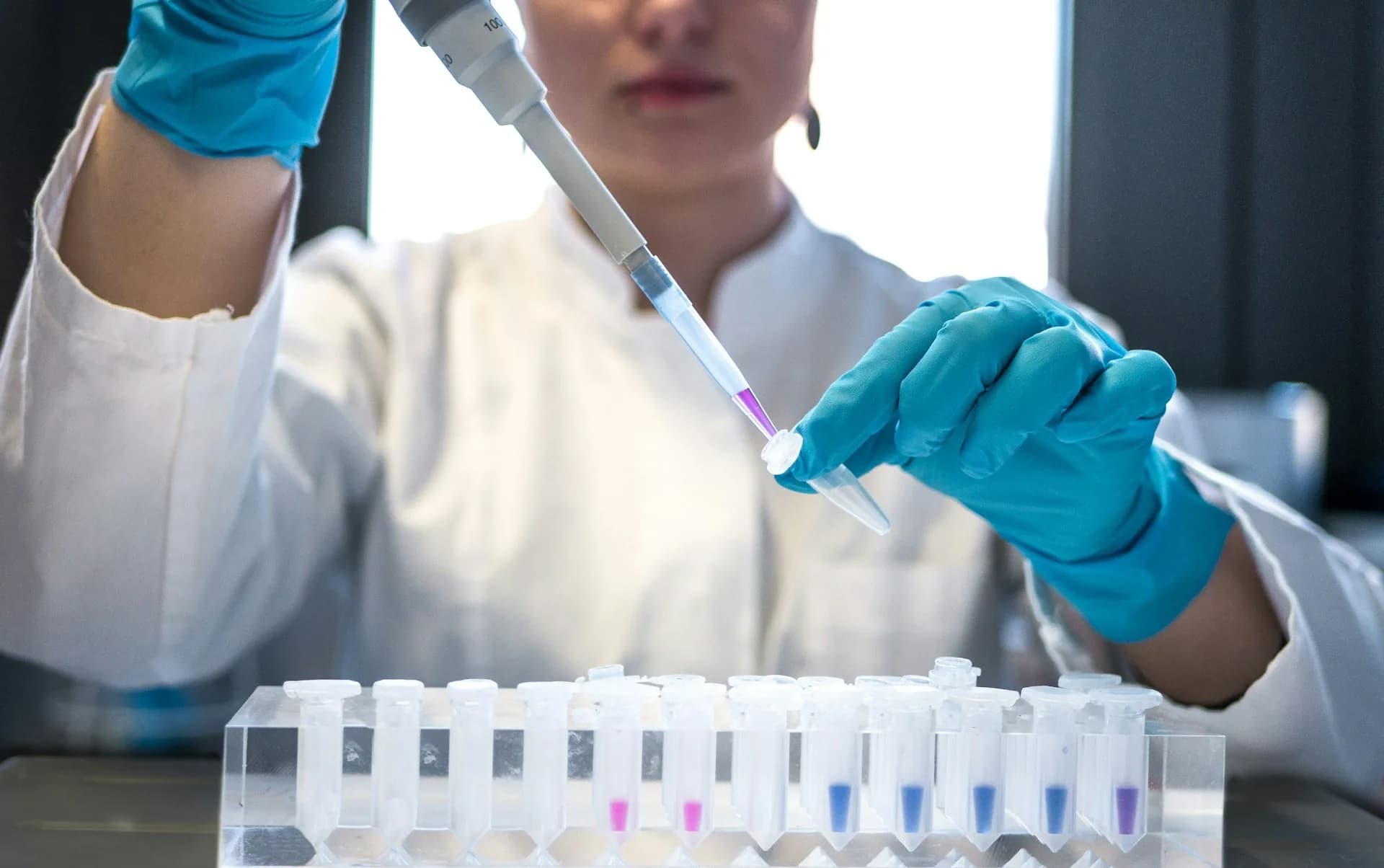 Científica usando una pipeta con tubos de ensayo en un laboratorio