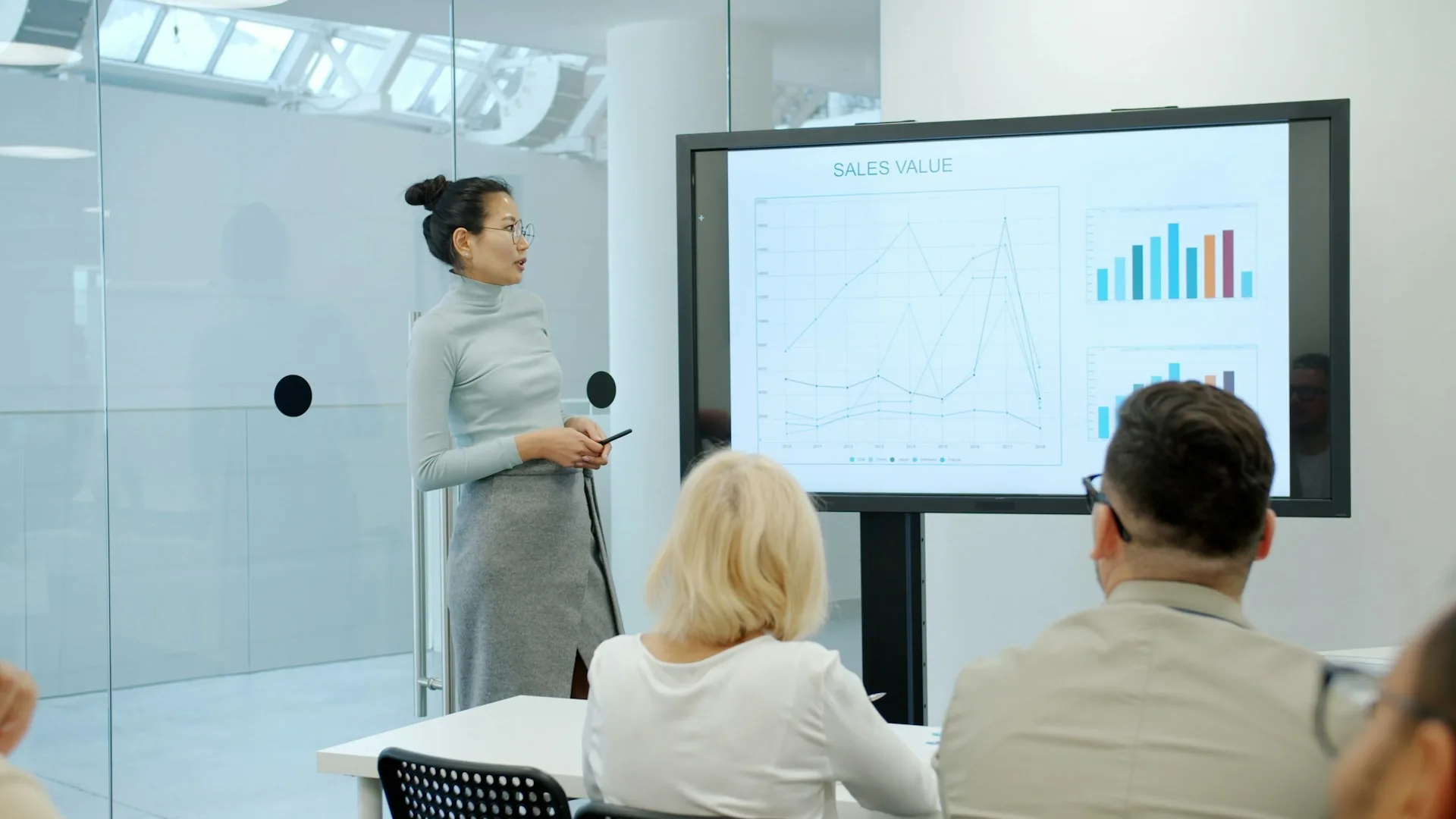 Mujer presentando una gráfica a una audiencia en una sala de conferencias corporativa